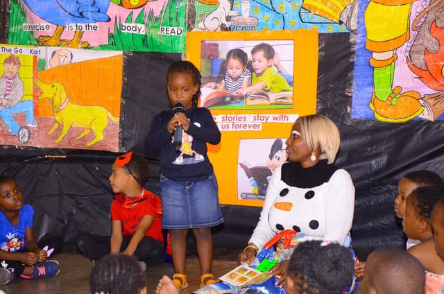 A young pupil reading aloud to classmates on DEAR Day
