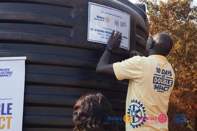 Rotarian unveiling a donated water tank at St. Gyavira Primary School Lweza